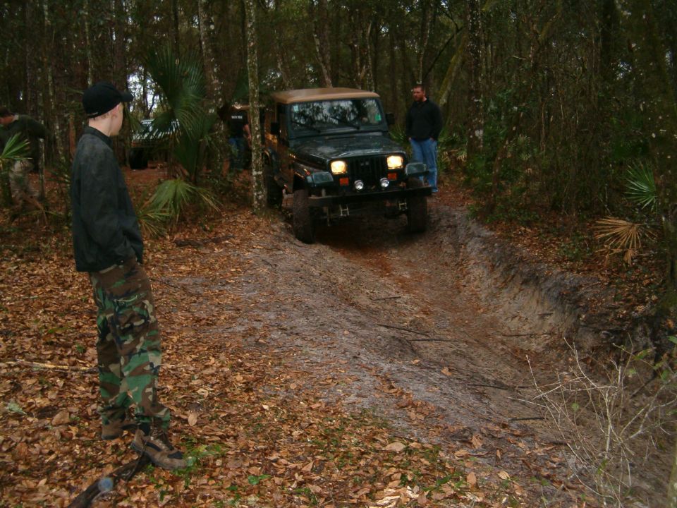 Jeep Wrangler TJ driving on a dirt trail in a wooded area