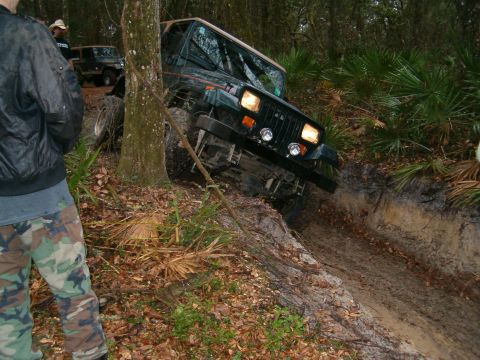 1991 Ford Bronco - A Jeep Wrangler navigates a challenging off-road trail, with another vehicle in the background.