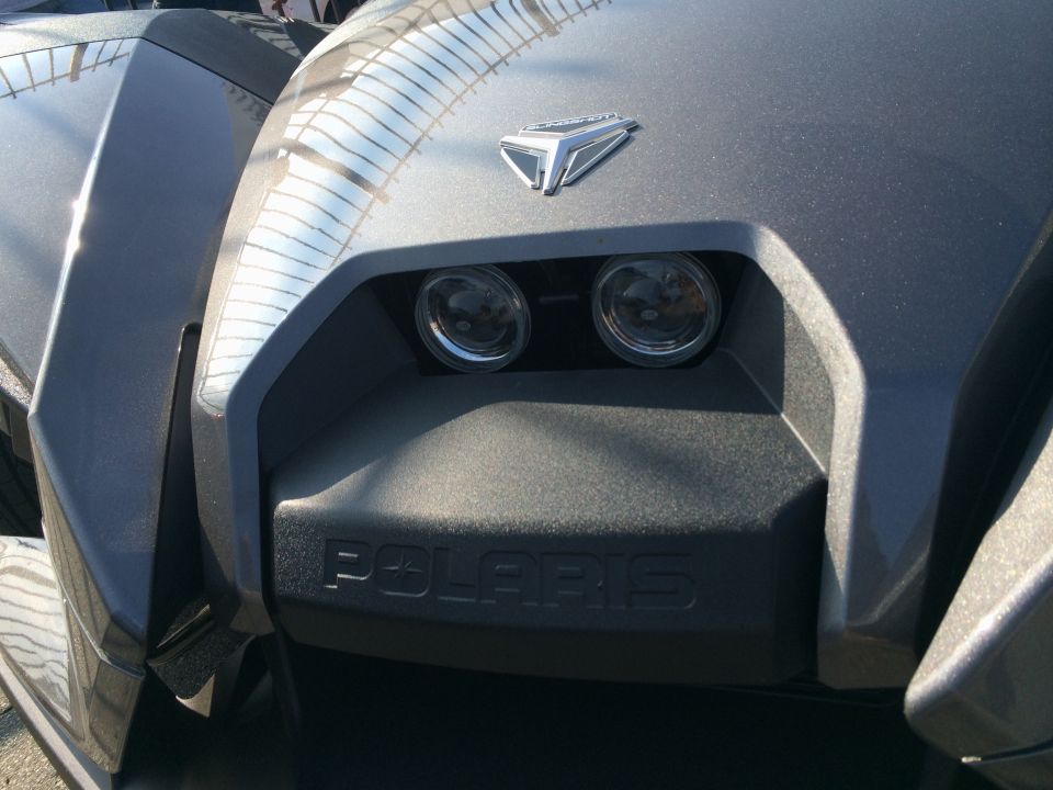 Close-up of a Polaris Slingshot's front end, showing the headlights and the 'POLARIS' branding