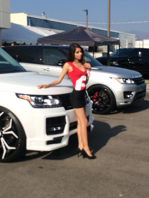 1968 Ford Mustang - A woman poses next to a white Range Rover at an outdoor event.