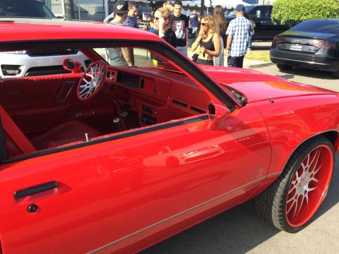 1968 Ford Mustang - Custom red interior and large wheels on a red car, seen from the side.