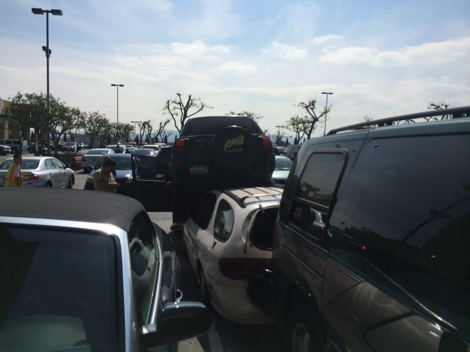 Dark green SUV parked next to a white car and a black convertible in a crowded parking lot