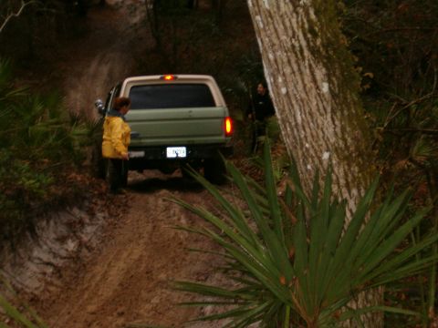 1991 Ford Bronco - A 1991 Ford Bronco navigates a muddy, wooded trail with two onlookers.