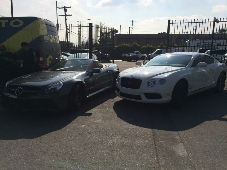 Dark convertible and white coupe parked on asphalt