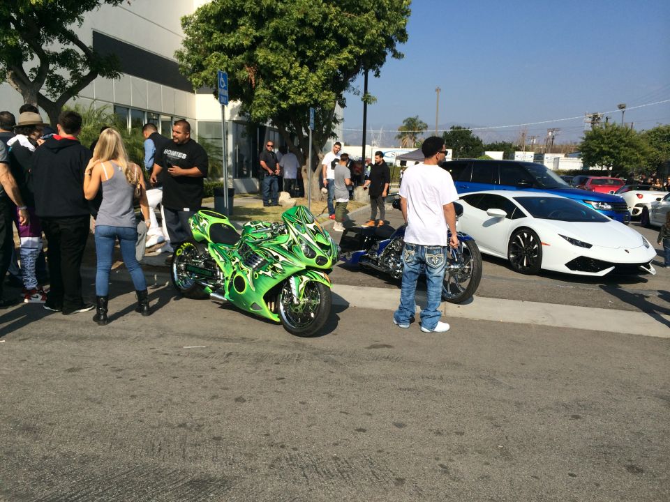 Green custom motorcycle parked on street with people around