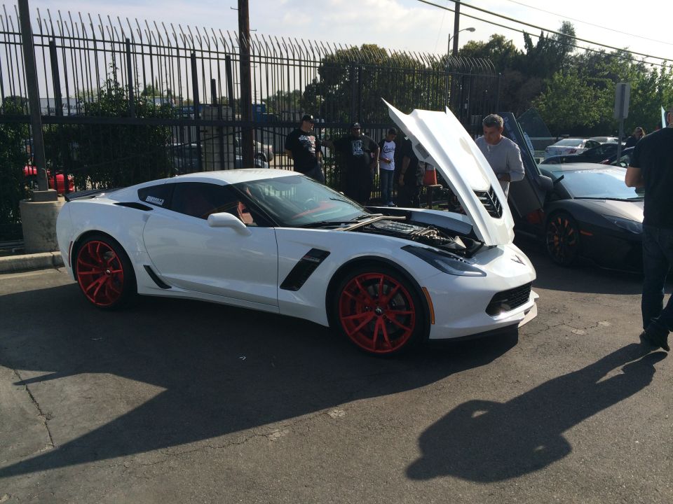 White Chevrolet Corvette Stingray with red wheels, hood open, parked outdoors