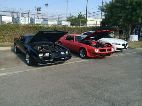 1968 Ford Mustang - Two classic Pontiac Firebirds and a modern BMW are parked side-by-side with their hoods open.