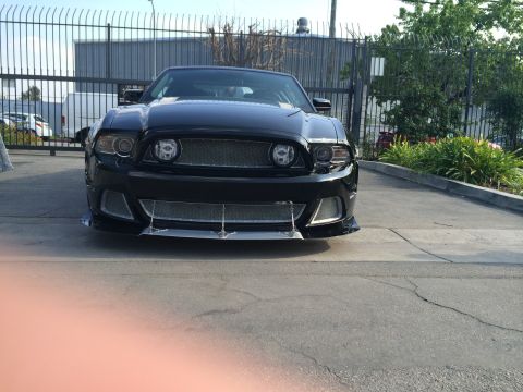 1968 Ford Mustang - Front view of a black custom car with an aftermarket grille and front splitter.