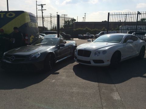 1968 Ford Mustang - Two luxury cars are parked side-by-side outdoors on a sunny day.