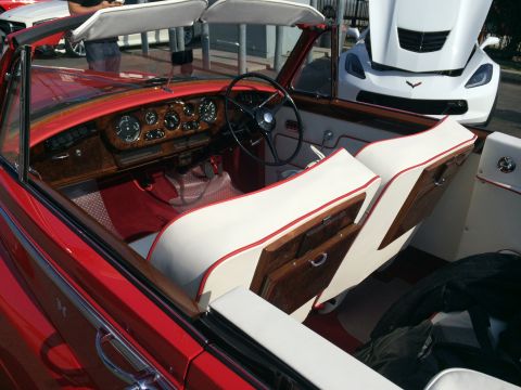 1968 Ford Mustang - Interior view of a red convertible wood trim and white upholstery, with a white Corvette visible in the background.