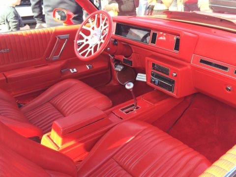 1968 Ford Mustang - The vibrant red interior of a classic car features plush seating and a custom steering wheel.
