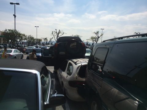 1968 Ford Mustang - A dark green SUV is parked tightly between other vehicles in a busy outdoor lot.
