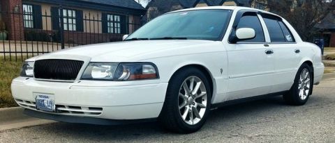 2000 Mercury Grand Marquis - White 2000 Mercury Grand Marquis sedan parked curbside, showing front and side profile.