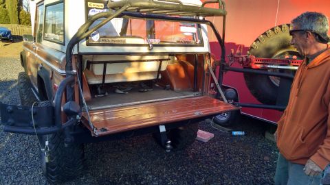 1985 Jeep CJ7 - This off-road SUV is shown from the rear with its tailgate open, revealing the interior and a roll cage.