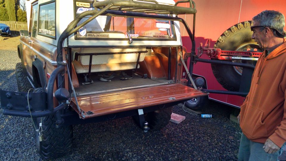 Rear view of brown off-road SUV with tailgate open and roll cage