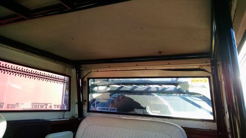 1985 Jeep CJ7 - The interior of a vehicle is shown, with a roll cage and stickers on the rear window.