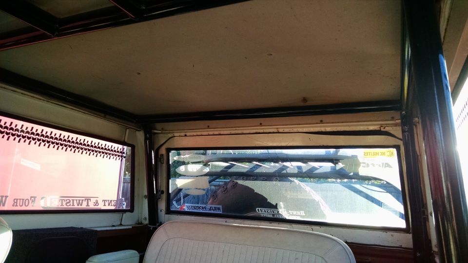 Interior view looking out rear window, showing roll cage and roof liner. Stickers visible on rear window