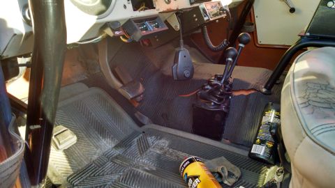 1985 Jeep CJ7 - Interior view of a vehicle, showing dual stick shifters, floor mats, and a radio.