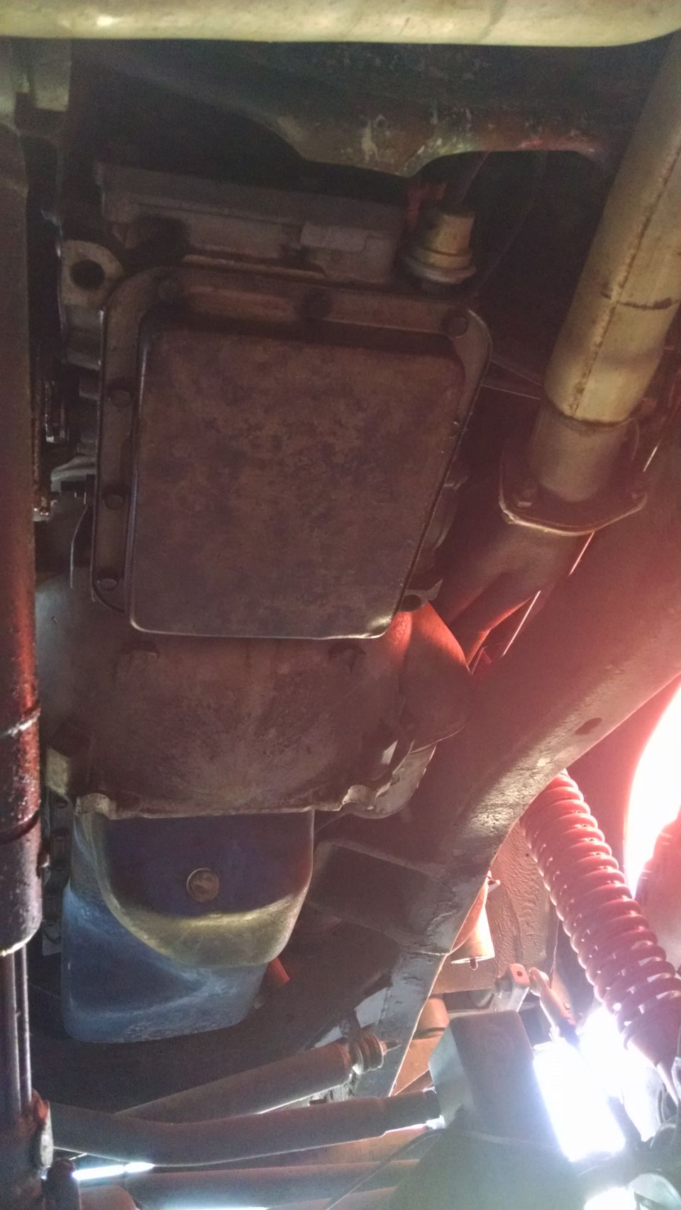 Undercarriage of a vehicle showing transmission pan, exhaust pipe, and suspension components