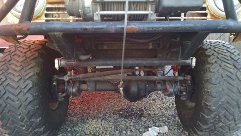 1985 Jeep CJ7 - Close-up view of the front axle, steering components, and winch on a heavily modified off-road vehicle.