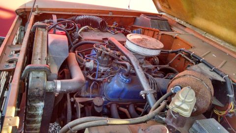 1985 Jeep CJ7 - The engine bay of an older vehicle shows a V8 engine with various hoses and wiring.