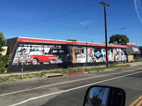 1968 Ford Mustang - A vibrant mural on a building features a classic red convertible alongside bowling-themed artwork.