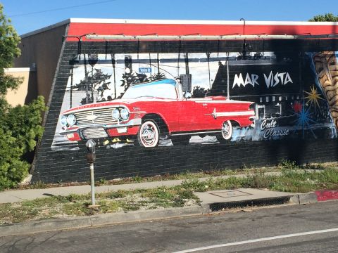1968 Ford Mustang - A mural on a brick wall depicts a red convertible with "MAR VISTA" and "Cult Classic" text, set against a backdrop of trees and buildings.