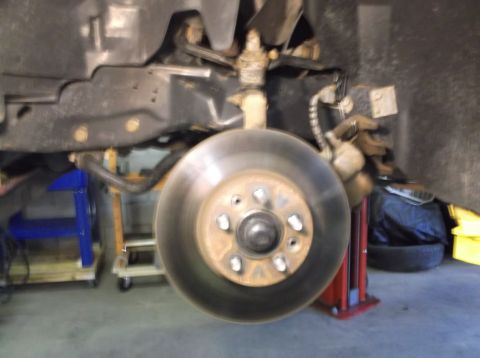 1999 Mercury Grand Marquis - Close-up view of a vehicle's front brake rotor and suspension system, indicating repair work.