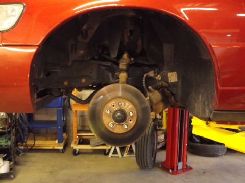 1999 Mercury Grand Marquis - Front wheel assembly of a 1999 Mercury Grand Marquis undergoing service on a lift.