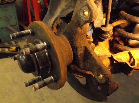 1999 Mercury Grand Marquis - Close-up of a heavily rusted wheel hub and associated suspension parts, suggesting a need for repair or replacement.