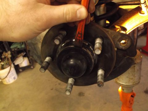 1999 Mercury Grand Marquis - A hand uses a tool on a vehicle's wheel hub assembly, likely during a repair.