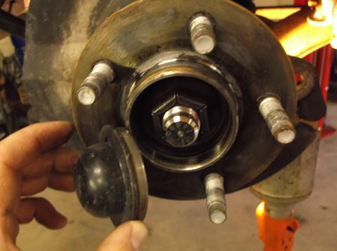 1999 Mercury Grand Marquis - Close-up of a wheel hub assembly with a hand removing a dust cap. The SuperMotors.net logo is visible in the lower right corner.