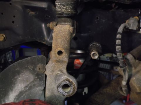1999 Mercury Grand Marquis - Close-up of a corroded vehicle suspension component with visible bolt holes.