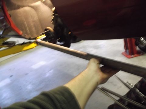 1999 Mercury Grand Marquis - A person is holding a metal bar underneath a vehicle, with a lift visible in the background.