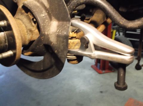 1999 Mercury Grand Marquis - A ball joint separator tool is shown attached to a vehicle's suspension system.