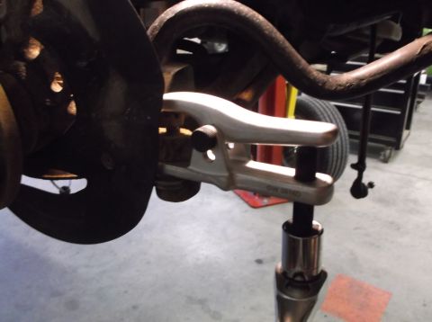 1999 Mercury Grand Marquis - A ball joint separator tool is being used on a vehicle's suspension system.