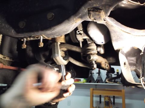 1999 Mercury Grand Marquis - Close-up of a mechanic's hands performing maintenance on a vehicle's suspension system.