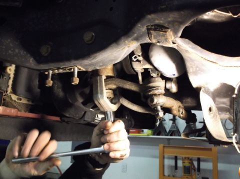 1999 Mercury Grand Marquis - Mechanic working on the front end suspension of a vehicle, focusing on a ball joint repair.