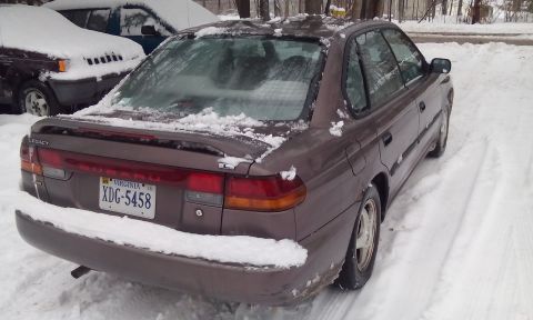 1996 Subaru Legacy - A 1996 Subaru Legacy sedan is parked in the snow, with another vehicle visible to its left.