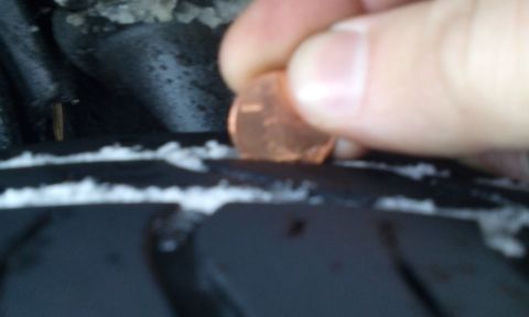 1996 Subaru Legacy - A penny is used to test the tread depth of a tire, indicating wear.