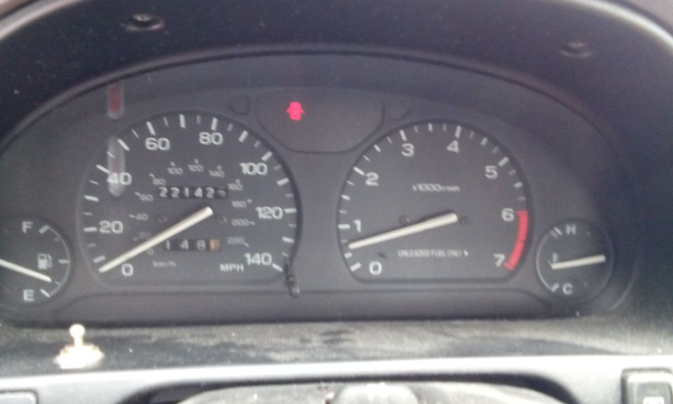 Car dashboard with speedometer, tachometer, fuel gauge, and warning lights. Odometer reads 221423