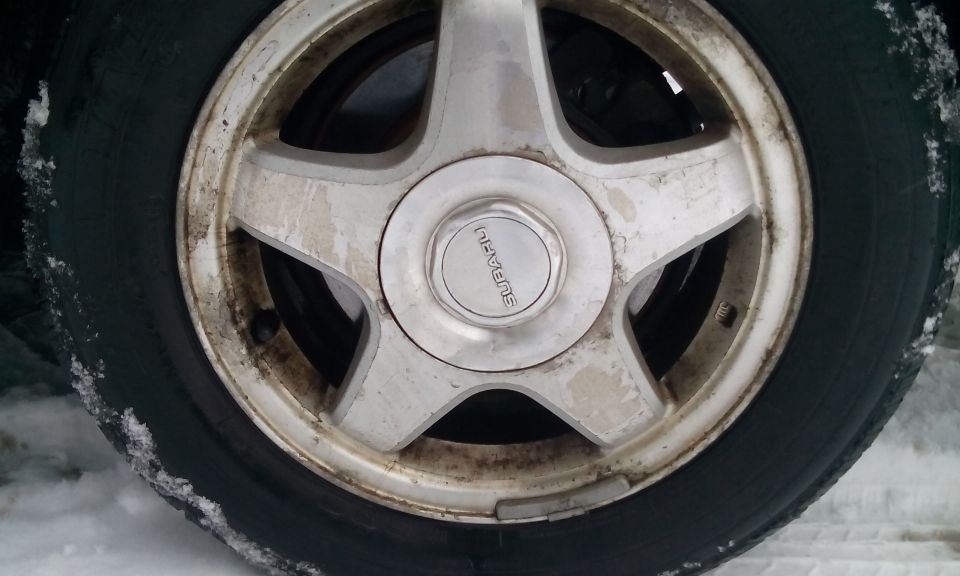 Close-up of a Subaru wheel with a tire, some dirt and snow on it