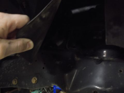 1999 Mercury Grand Marquis - A hand holds a black plastic part near the vehicle's frame, possibly during a front-end rebuild.