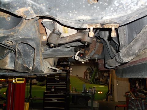 1999 Mercury Grand Marquis - Undercarriage view of a vehicle with suspension parts and exhaust system visible, with another car in the background.