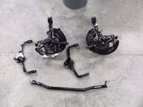 1999 Mercury Grand Marquis - Various black painted car suspension parts laid out on a concrete surface, likely after a rebuild or refinishing.