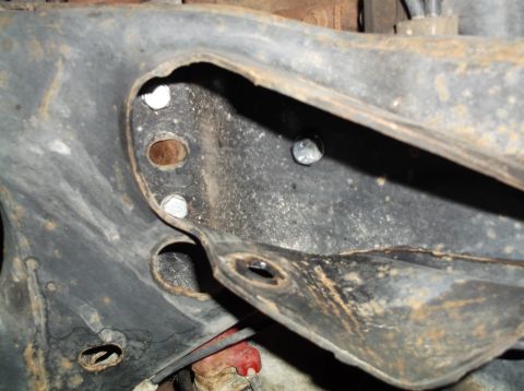 1999 Mercury Grand Marquis - Close-up of a rusty metal vehicle frame component with several bolts, likely part of a suspension or chassis system.