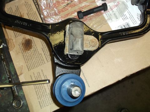 1999 Mercury Grand Marquis - Close-up of a vehicle's control arm assembly, a blue ball joint and rubber bushings, likely for a front-end rebuild.
