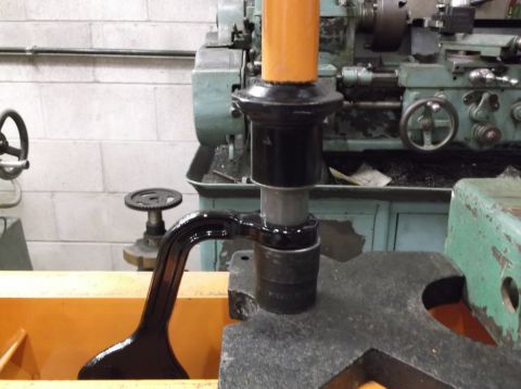 1999 Mercury Grand Marquis - A black metal part, possibly a suspension component, is being worked on by industrial machinery in a workshop.