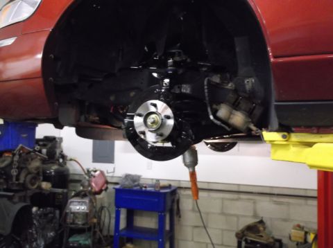 1999 Mercury Grand Marquis - Close-up of a vehicle's brake system during repair, showing the rotor and suspension components.