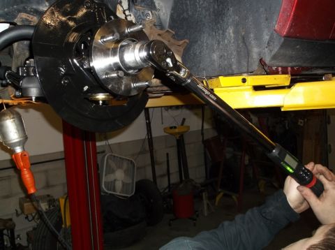 1999 Mercury Grand Marquis - Mechanic uses a digital torque wrench on a vehicle's brake rotor and hub assembly during a front-end rebuild.
